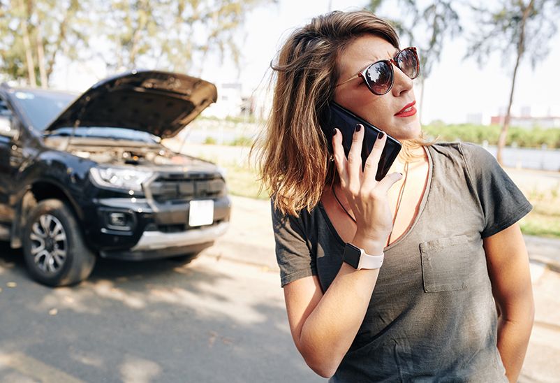 Insurance Excess woman calling insurance company with crashed car in the background